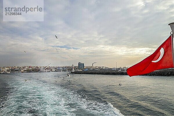 Beautiful view from the passenger ship to the Kadikoy district of Istanbul with seagulls and the red national flag of Turkey. Pier in right side