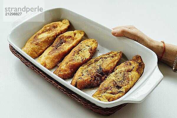 Female hand holding a tray with torrijas  a typical Spanish sweet fried toasts of sliced bread soaked in eggs and milk  on white background. Traditional dessert for Lent and Easter