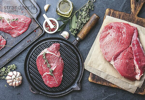 Food  Fresh raw meat. Beef Tenderloin and marbled beef steaks on grill pan and frying board with seasoning  black background top view