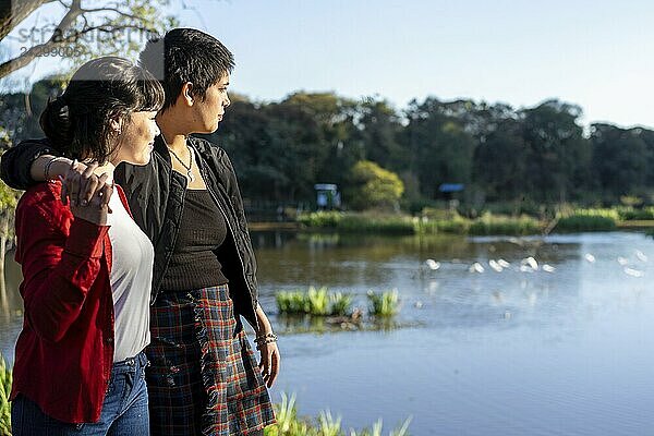 Romantic LGBT couple of young women embracing each other while gazing at the lake