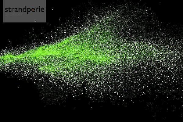 Green color powder explosion cloud on black background.Green dust splash on dark background