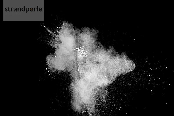 Freeze motion of white dust particles on black background. White powder explosion