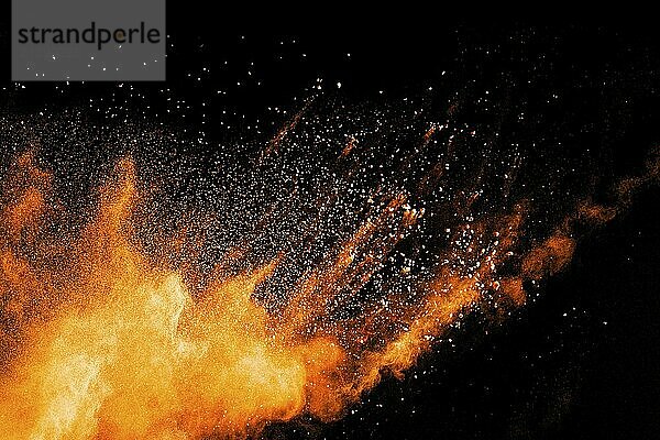 Abstract orange powder explosion on black background. Freeze motion of orange dust particles splash