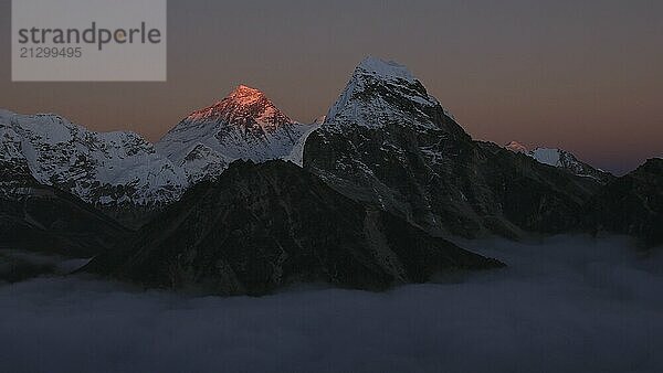 Bright lit Mount Everest surrounded by a sea of fog