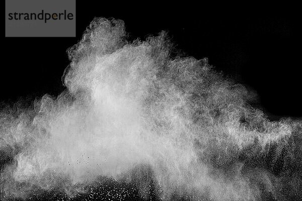 Freeze motion of white dust particles on black background. White powder explosion