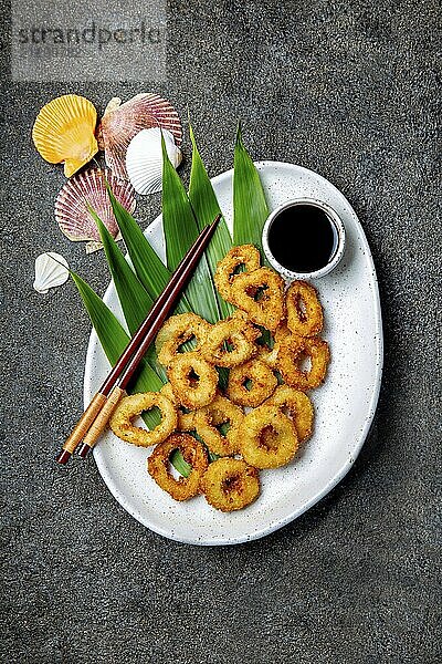 Food  Food  Fried squids rings on white plate decorated with tropical leaves  gray concrete background  top view