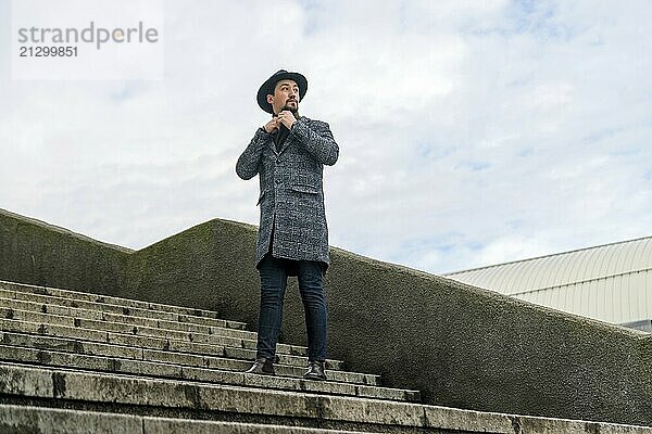 Portrait of a stylish handsome young man with a coat outdoors. A man wearing a coat and a scarf looking away and wondering