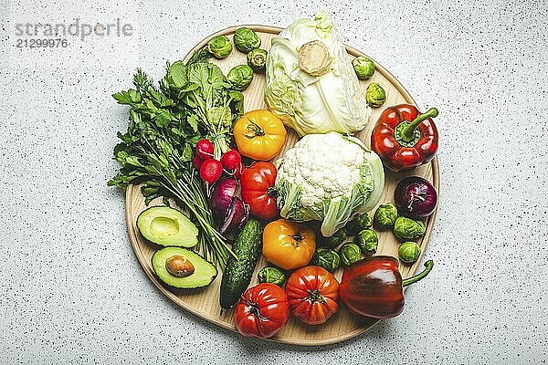 Rustic wooden tray with selection of fresh vegetables and greenery on white kitchen table top view. Vegetarian or diet food from organic ingredients  healthy nutrition concept  food photography  food photography