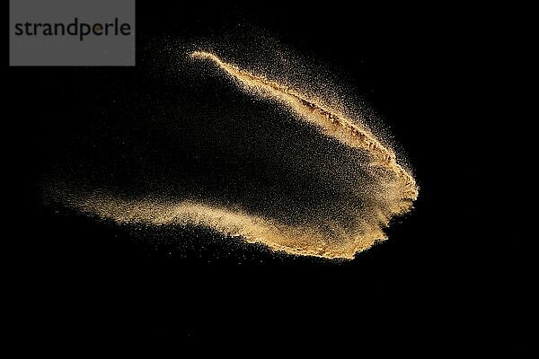 Brown color sand splash against black background. Sand fly wave in the air