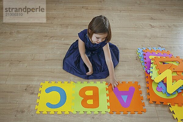 A young girl playing with letters of the alphabet viewed from above themes of learning education alphabet