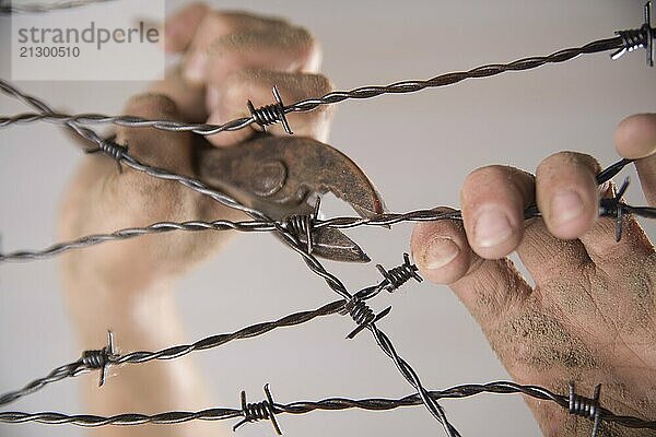 Hands gripping the barbed wire in the sign to run away with the white background