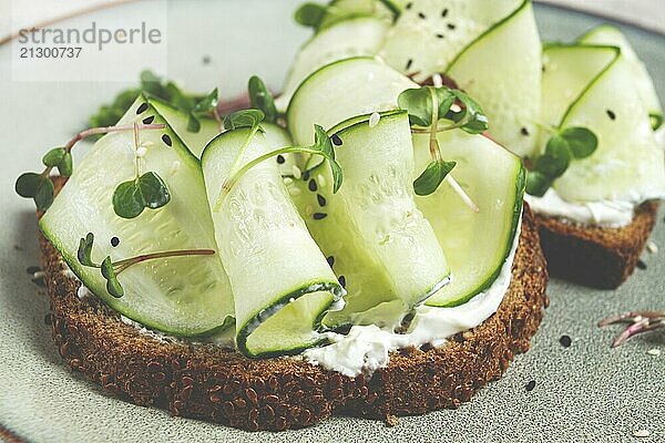 Food  Breakfast  cereal bread sandwiches  cream cheese  sliced cucumber  with micro greenery on a light table  close-up  top view  selective focus  no people