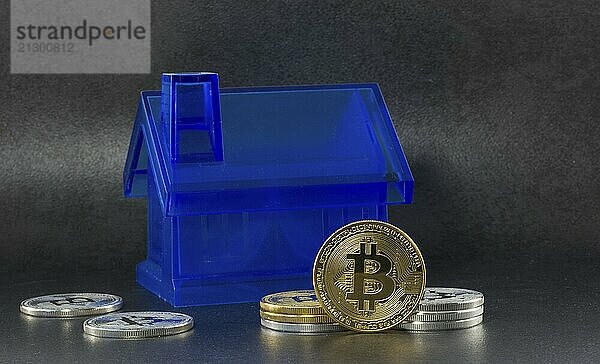 Litecoin and bitcoin for buying a houses with black background with a single litecoin facing the camera in sharp focus with shading on the icon letter B on the face of the bit coin