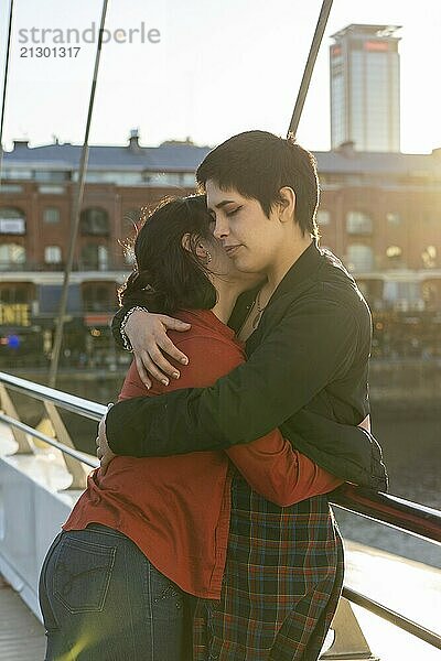 Affectionate young LGBT couple of women sharing an embrace on a bridge