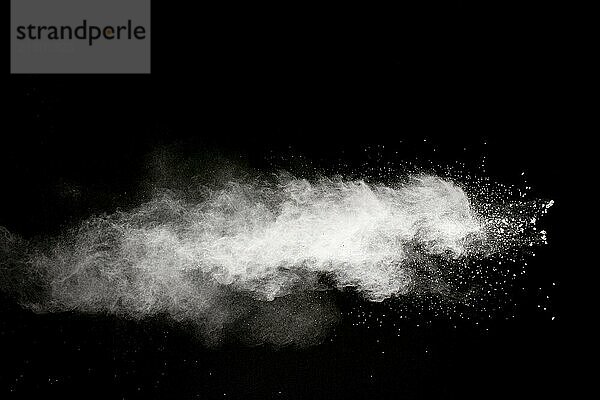 White powder explosion cloud against black background.White dust particle splash