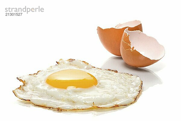 Fried egg on a white background with brown eggshells