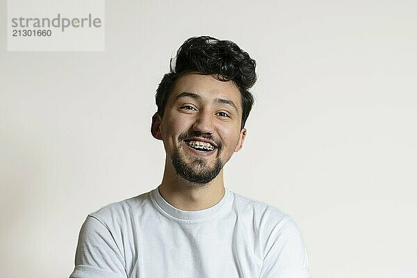 Portrait of a young man with braces smiling and laughing. A happy young man with braces on a white background