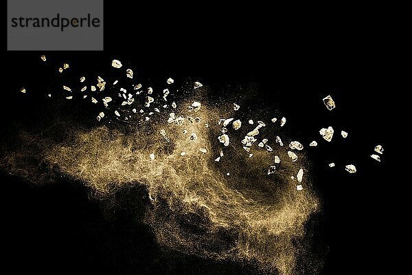 Split debris of stone exploding with brown powder against black background