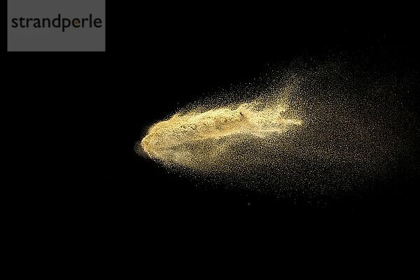 Abstract sand cloud. Golden colored sand splash against dark background