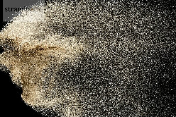 Dry river sand explosion. Golden colored sand splash against black background