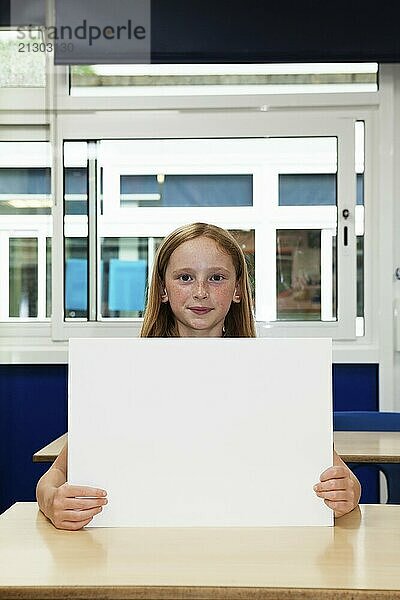 Primary school caucasian girl holding blank placard