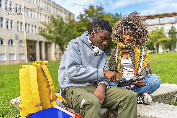 Two male and female university students using digital tablet outside the campus