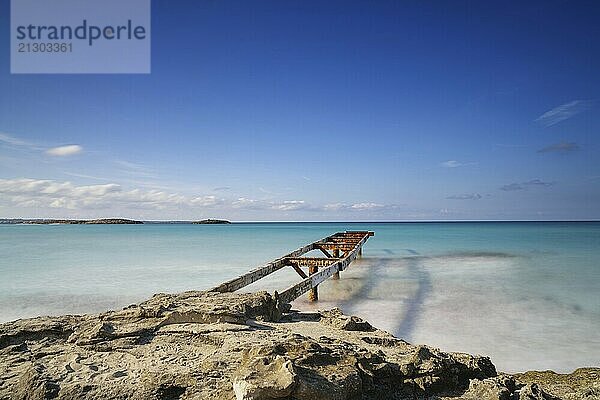 An old dock leads out into the turquoise waters of the Ses Illetes Beach in northern Formentera