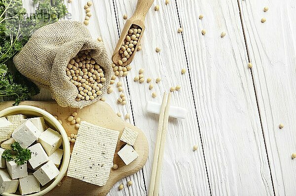 Soy Bean curd tofu in clay bowl and in hemp sack on white wooden kitchen table. Non-dairy alternative substitute for cheese. Place for text