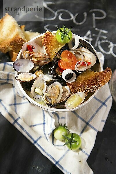 Presentation of a soup with seafood on a black background with writing