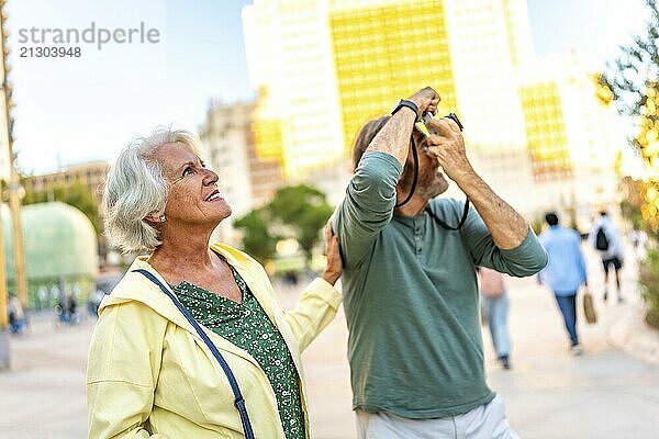 Senior man talking a photo with a digital camera while visiting the city with his partner