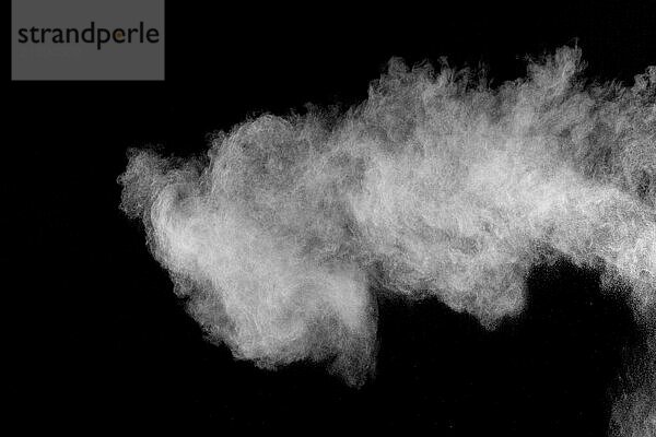 Bizarre forms of white powder explosion cloud against black background.White dust particles splash