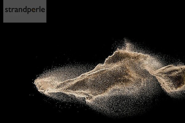 Dry river sand explosion. Golden colored sand splash against dark background