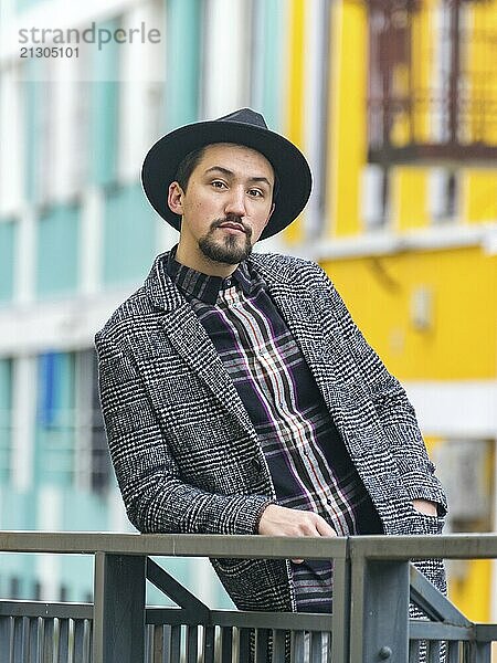 Portrait of a stylish handsome young man with a coat outdoors. A serious man wearing a coat  hat and a shirt looking confident at the camera