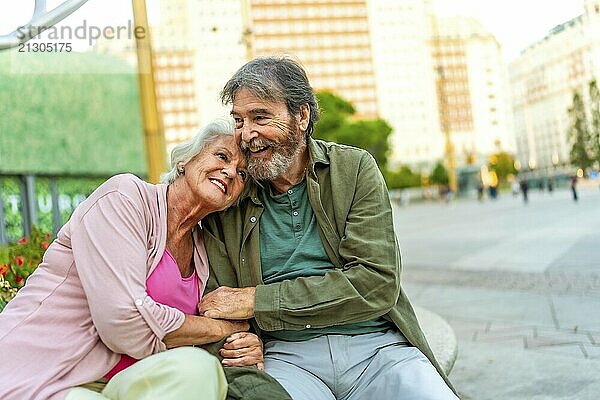 Portrait with copy space of a cute mature couple sitting on bench embraced in the city