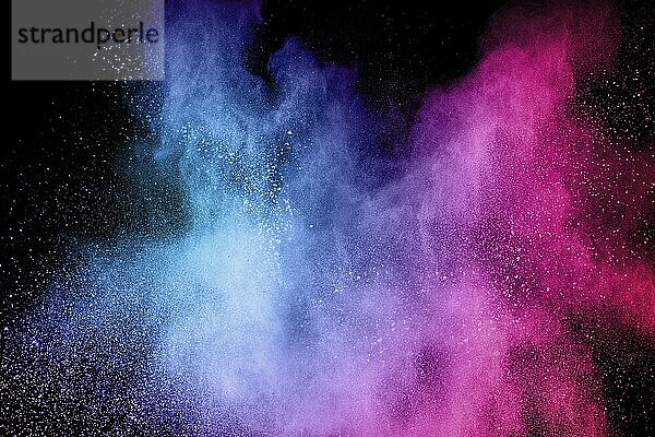 Multicolored powder explosion on black background.Blue pink dust particles splattered