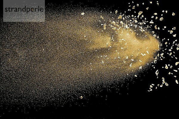 Dry river sand with stone explosion. Golden colored sand splash against dark background