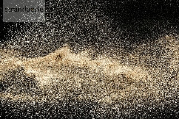 Dry river sand explosion. Golden colored sand splash against black background