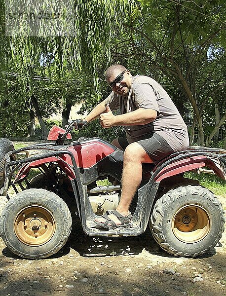 Fun overweight man sitting on quad bike atv