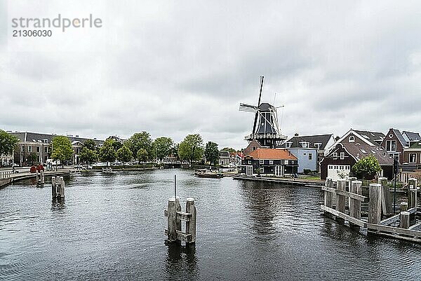 Haarlem  Netherlands  August 3  2016: Picturesque cityscape with beautiful traditional house  windmill and vessels in canal of Haarlem