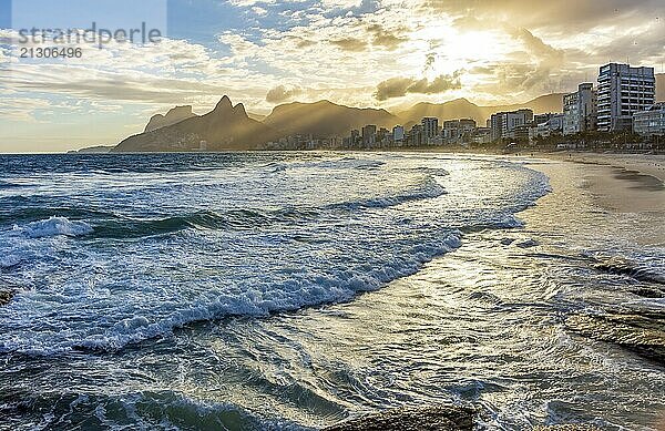 Sunset on Ipanema beach in Rio de Janeiro with its buildings in front and mountains in the background