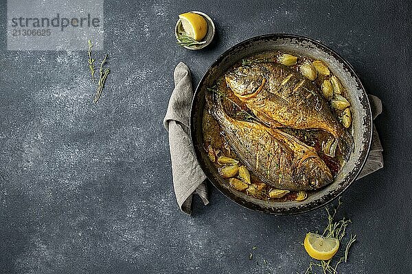 Food  Food  Baked sea bream or dorada with onion and herbs in pan on dark background