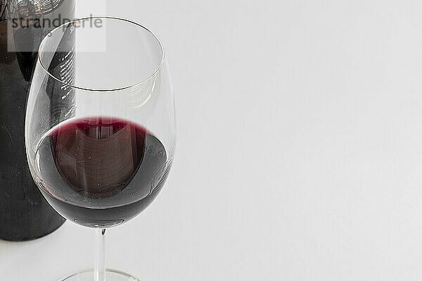 Close up of glass and bottle of red wine on white background. Copy space