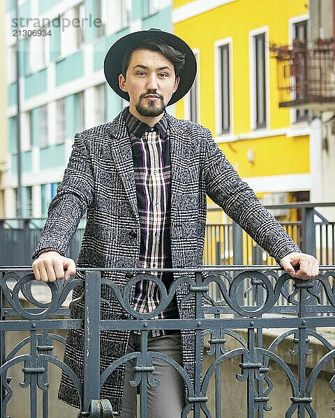 Portrait of a stylish handsome young man with a coat outdoors. A serious man wearing a coat  hat and a shirt looking confident at the camera