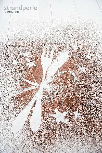 Representation of the Christmas holiday with cutlery on white background and a dusting of cocoa