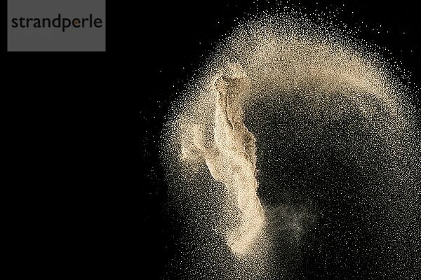 Dry river sand with stone explosion. Yellow colored sand splash against dark background