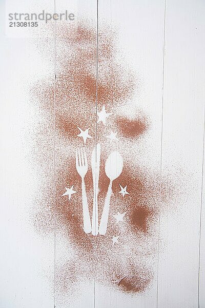 Representation of the Christmas holiday with cutlery on white background and a dusting of cocoa