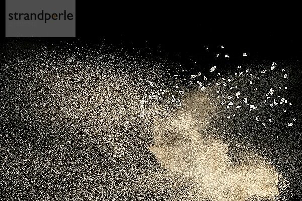 Dry river sand with stone explosion. Golden colored sand splash against dark background