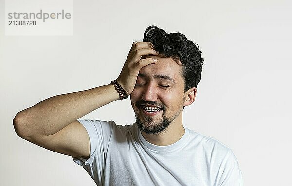 Portrait of a young man with braces smiling. A happy young man with braces on a white background