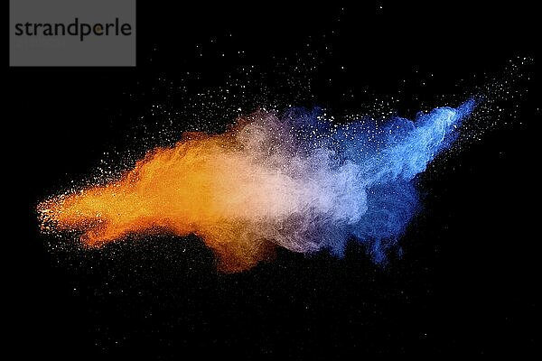 Blue orange color powder explosion cloud on black background. Closeup of Blue orange dust particles splash