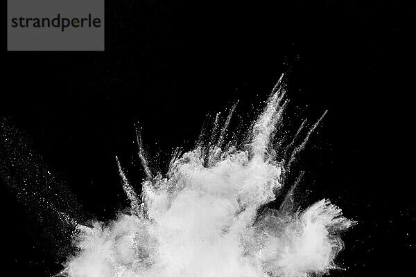 White powder explosion cloud against black background. White dust particles splash